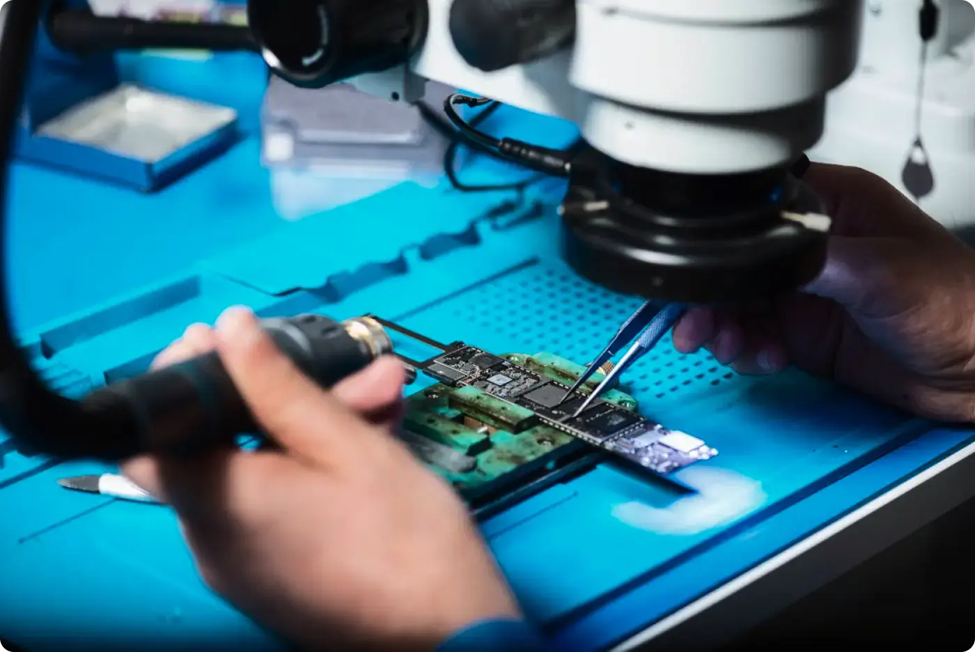 Technician assembling electronic circuit board under microscope